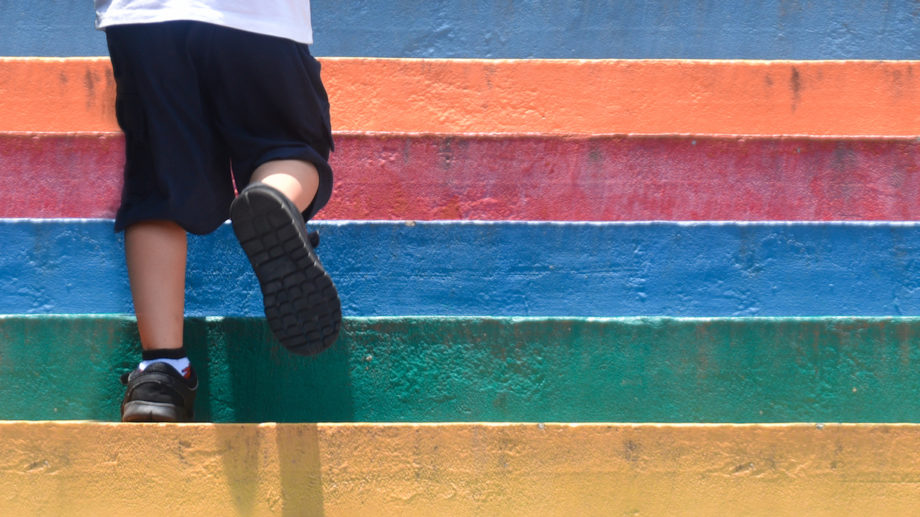 Lower part of a boy in casual shoe walking up outdoor colorful staircase,children lifestyle successful concept