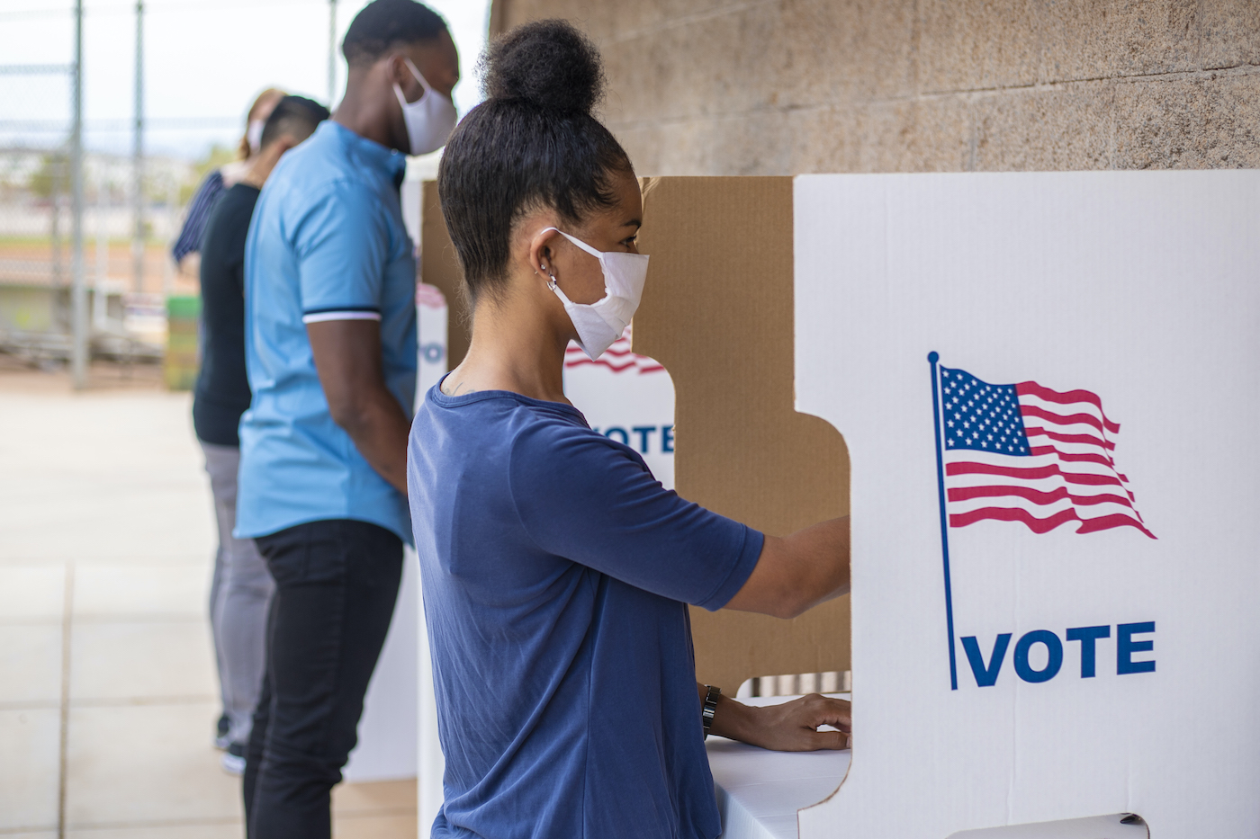 Voting photo showing a row of voters standing at voting booths