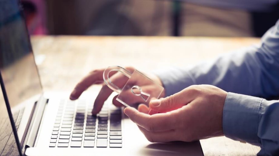 Close up image of hands typing on keyboard. One hand is holding a clear lock.